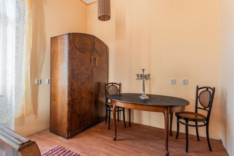 The interior of a cabin with wooden floor decor, an antique table, two chairs, and a wardrobe.