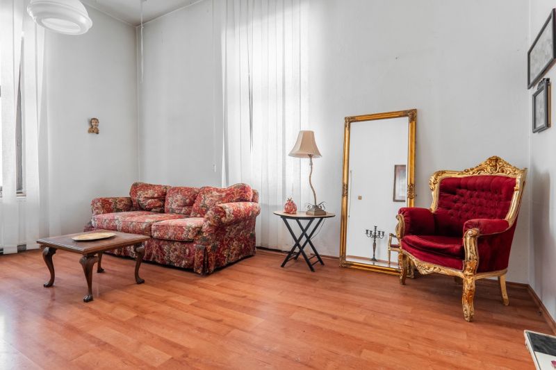 Living room in a cottage with a patterned sofa, mirror, and floor with wooden decor.
