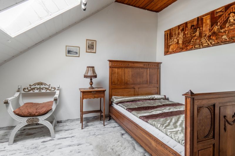 A room in a cottage with antique wooden furniture, a floor with a wooden decor, and a sloped ceiling.