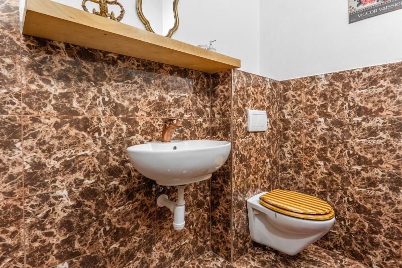 A bathroom in a cabin with marble cladding, a sink, and a toilet with a wooden decor.