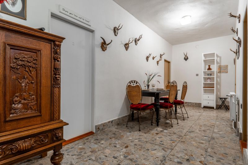 The interior of the cabin with a stone floor, hunting trophies, and a carved wooden cabinet.