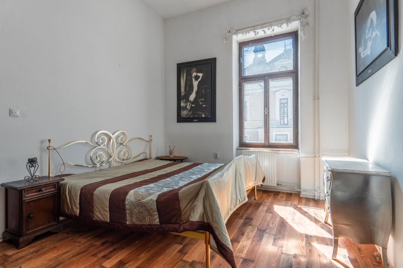 A bedroom in a cottage with a bed, a decorative dresser, and a floor with a wooden decor.