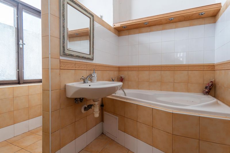A bathroom in a cabin with a bathtub, sink, and window. Tiles in soft tones.