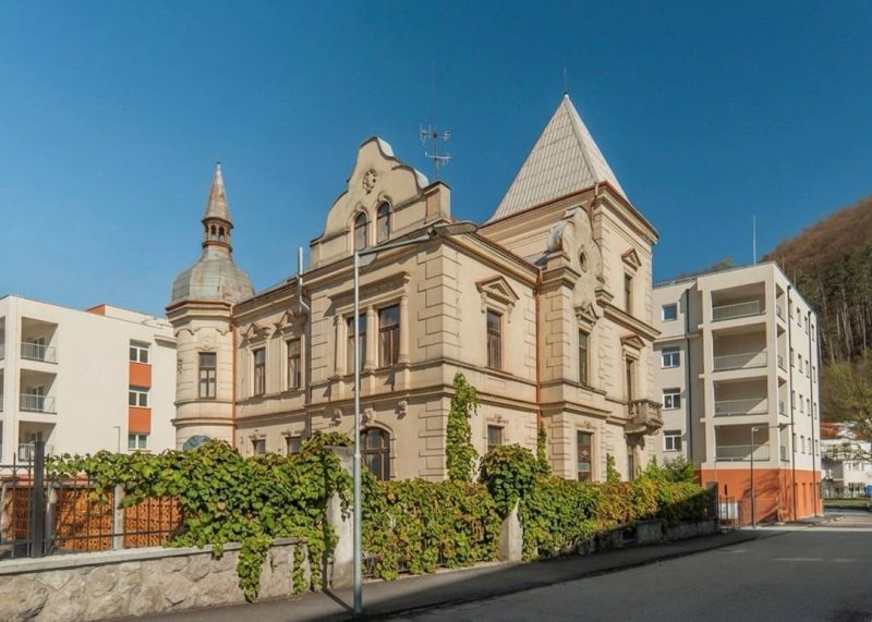A historical building in Trenčianske Teplice next to modern apartment buildings.