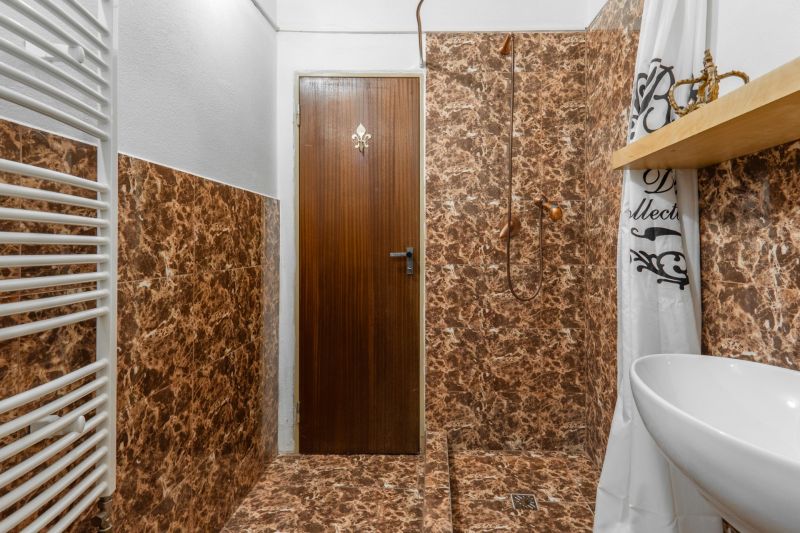 Bathroom in a cottage with marble tiles and a white radiator.