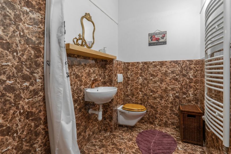 A bathroom in a cabin with marble decor wallpaper, a mirror, and a sink.
