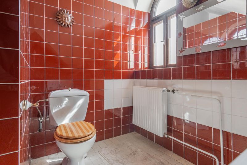 Bathroom in a cabin with red and white tiles, a mirror, and a toilet.