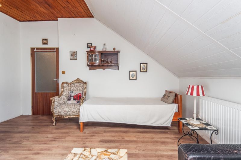 Interior of a cottage with a wooden decor floor, an armchair, and decorations on the wall.