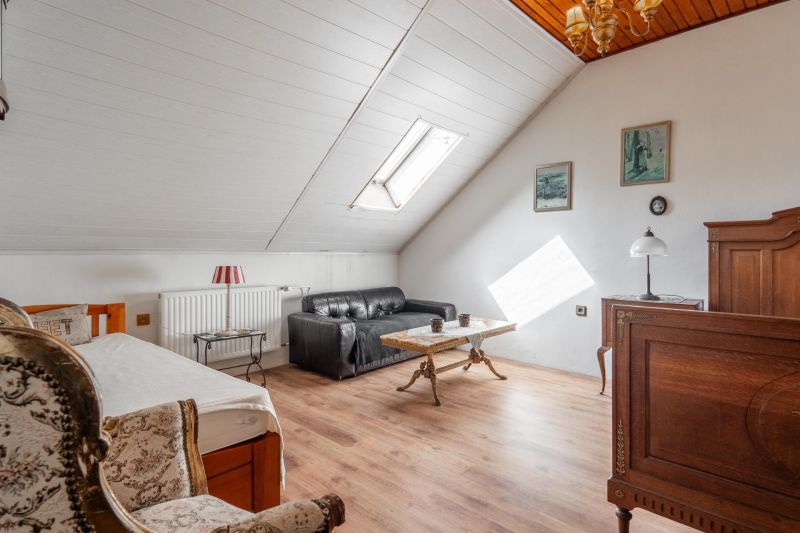 A room in a cottage with a wooden floor, a sofa, and antique furniture.