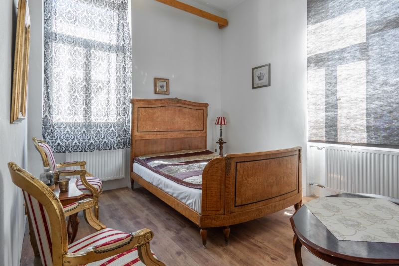A bedroom in a cabin with wooden furniture, patterned curtains, and a floor with a wooden design.