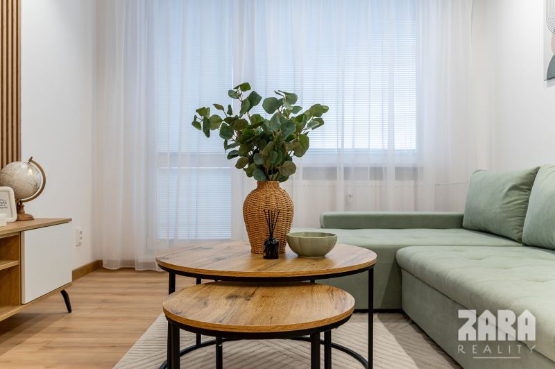 Living room in a 2-room apartment with a sofa, tables, and a floor with a wooden decor.