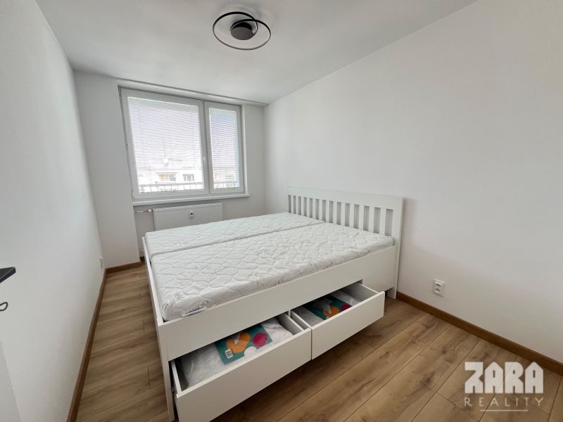 Bedroom in a 2-room apartment with a bed and a wooden decor floor.