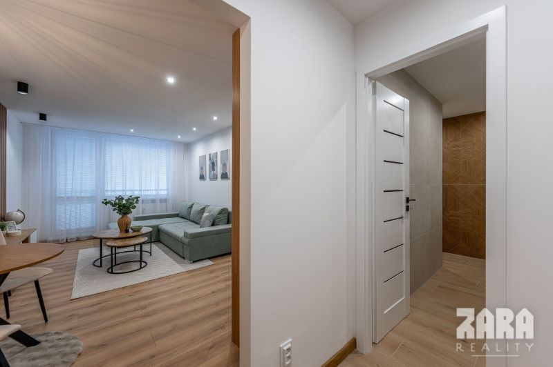 Interior of a 2-room apartment with a wooden decor floor and a spacious sofa in the living room.