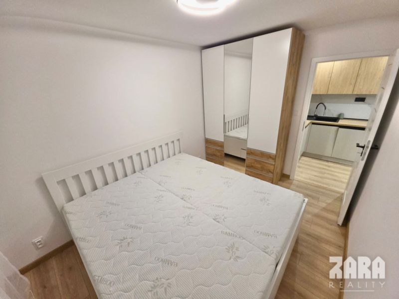 Bedroom with a bed, built-in wardrobe, and a view of the kitchen in a 2-room apartment.