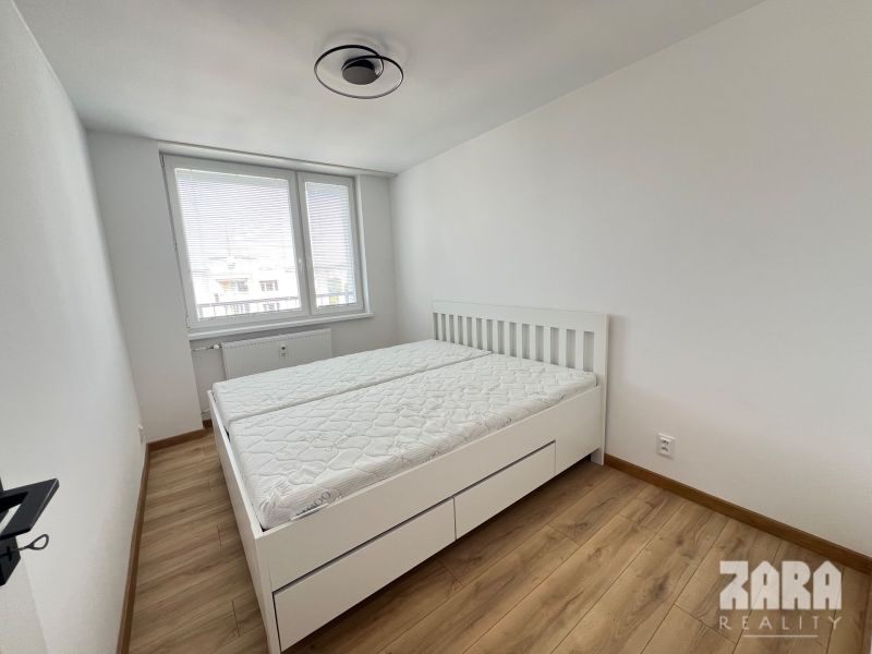 A bedroom with a bed, mattresses, and a wooden decor floor in a two-room apartment.