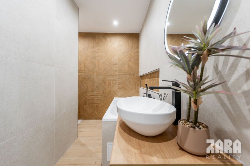 Bathroom in a 2-room apartment with a sink, mirror, and floor with a wood decor.