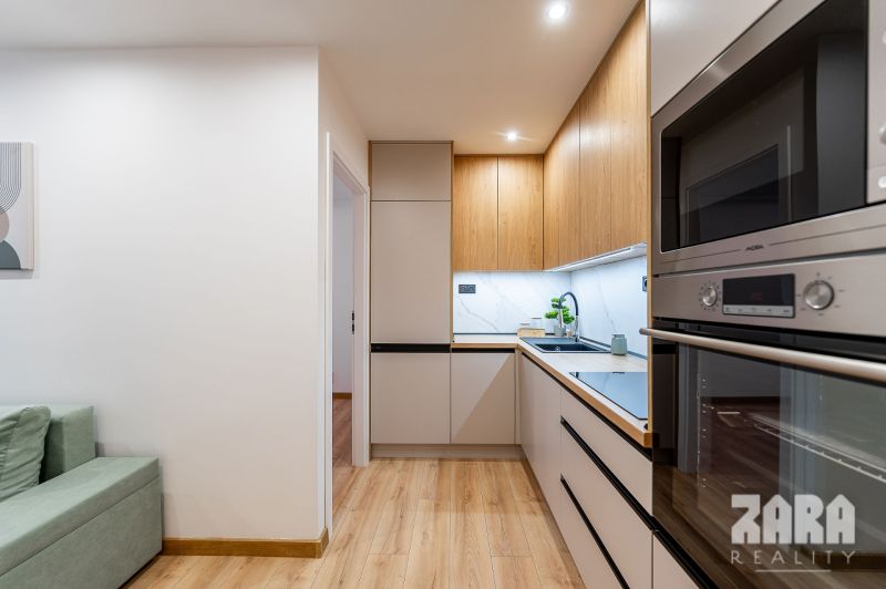 Interior of a 2-room apartment with a kitchen unit and a wooden decor floor.