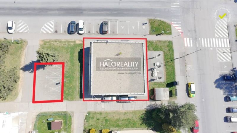 A building with commercial spaces and a parking lot in Žiar nad Hronom at the intersection of streets.