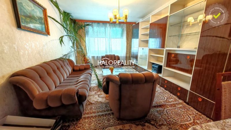 Living room of a 4-room apartment with a wooden decor floor, a sofa, and a dining table.