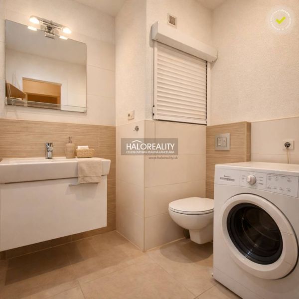 Bathroom in a studio apartment with a sink, washing machine, and mirror.