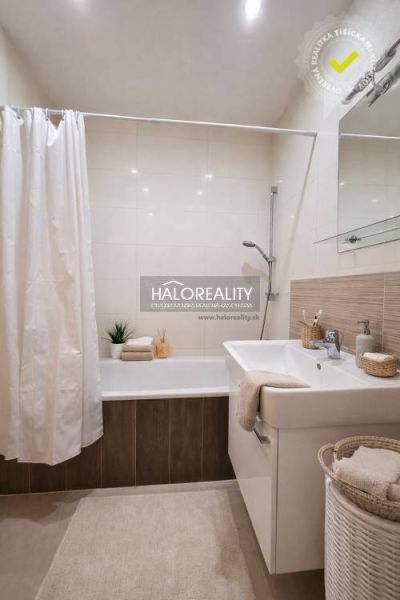 Bathroom with a bathtub, sink, and laundry basket in a studio apartment.