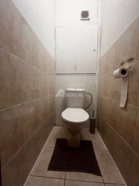A toilet with light tiles in a 2-room apartment.