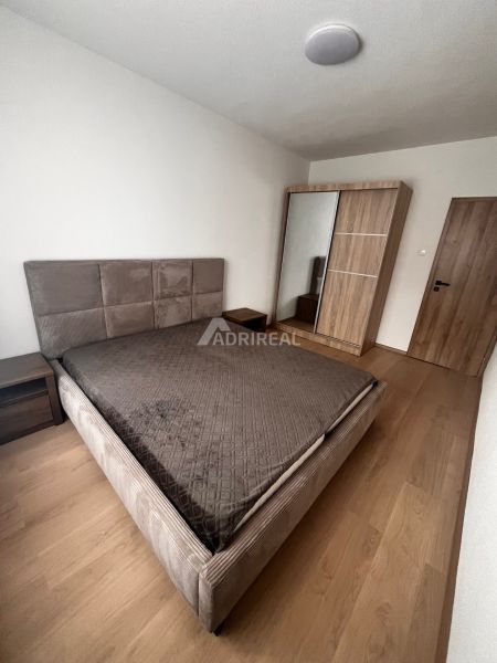 Bedroom in a 2-room apartment with a bed and a wardrobe, floor with wood decor.