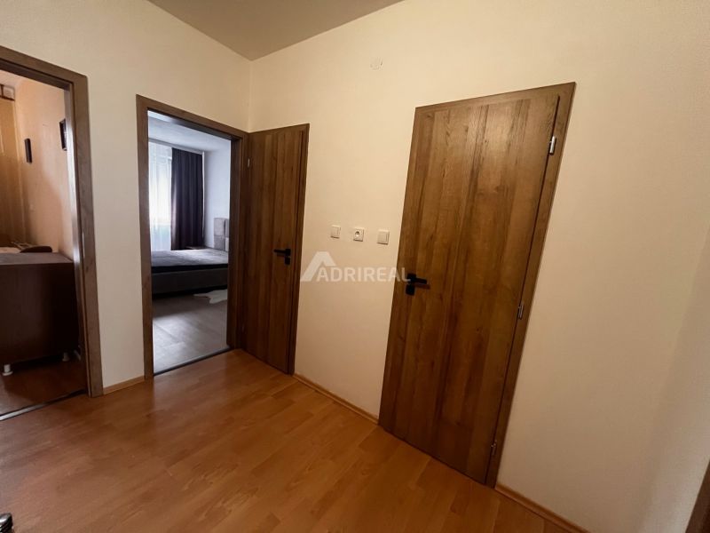 A hallway in a 2-room apartment with a wooden decor floor and wooden doors.
