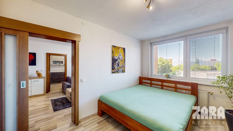 A bedroom in a three-room apartment with a wooden decor floor and large windows.