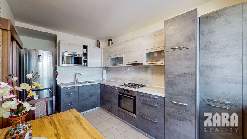 A kitchen in a 3-room apartment with a kitchen unit, table, and floral decoration.