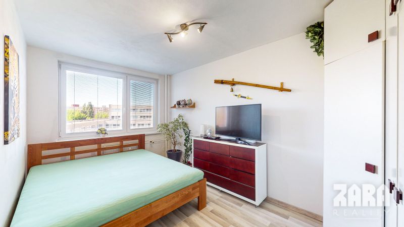 Bedroom in a 3-room apartment with a bed, television, dresser, and floor with a wooden decor.