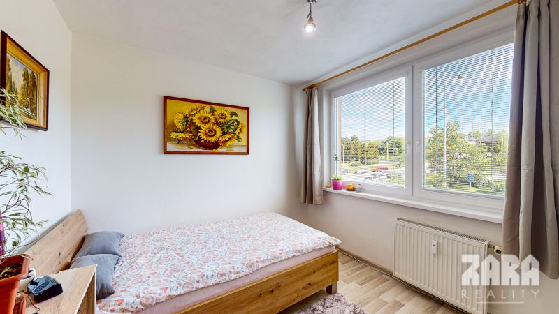 A bright room with a bed and a painting of sunflowers in a 3-room apartment.