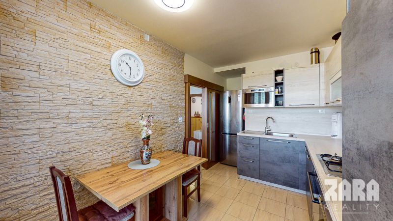 A kitchen with stone cladding, a wooden table, and a modern kitchen unit in a 3-room apartment.