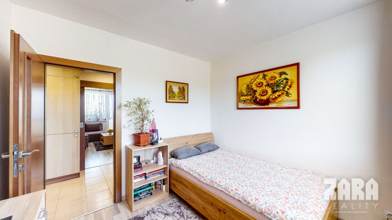 A room in a 3-room apartment with a bed, a shelf, and pictures on the walls.