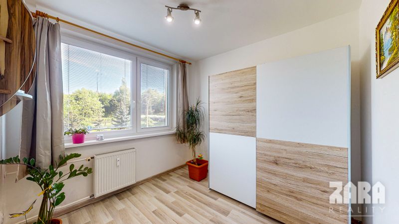 A room in a 3-room apartment with a large window, a wardrobe, and a floor with a wooden decor.