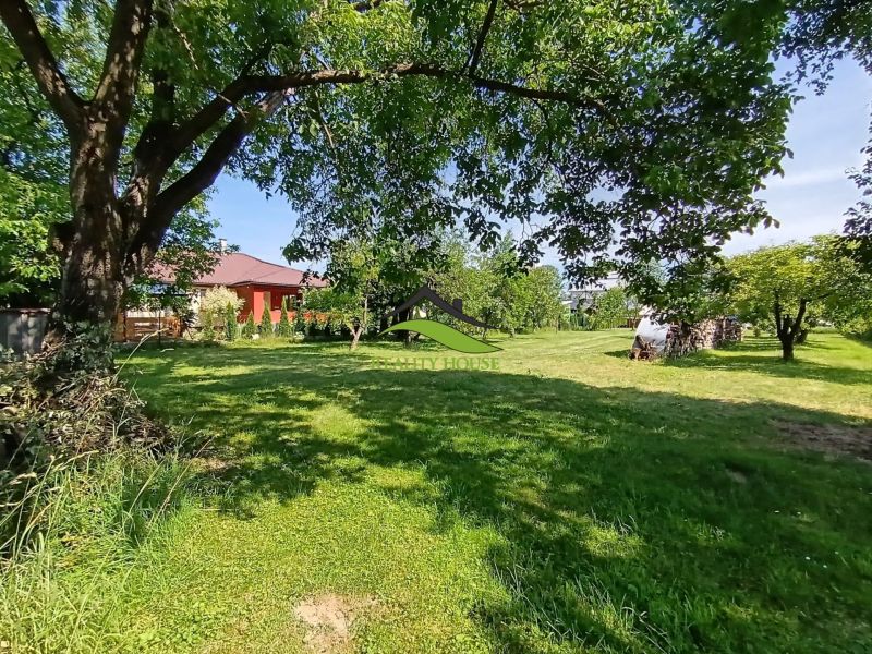A garden with trees and a house in the background in Strážske, designated for residential land.
