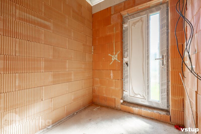 A room in an unfinished family house with brick walls and plastic doors.