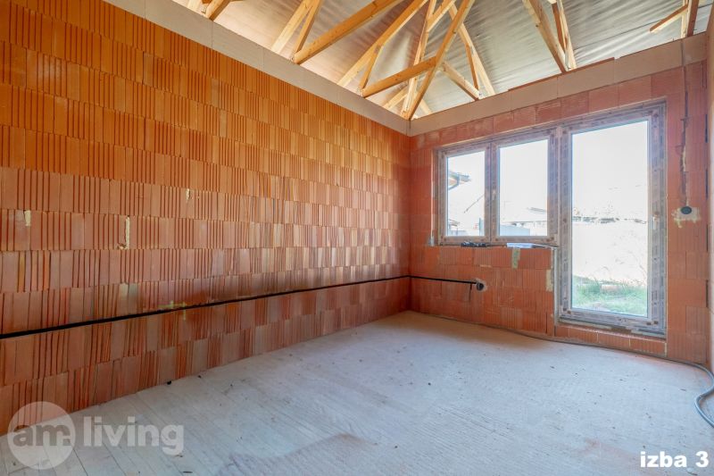 A room in a family house with a window, a brick wall, and a floor with a wooden design.