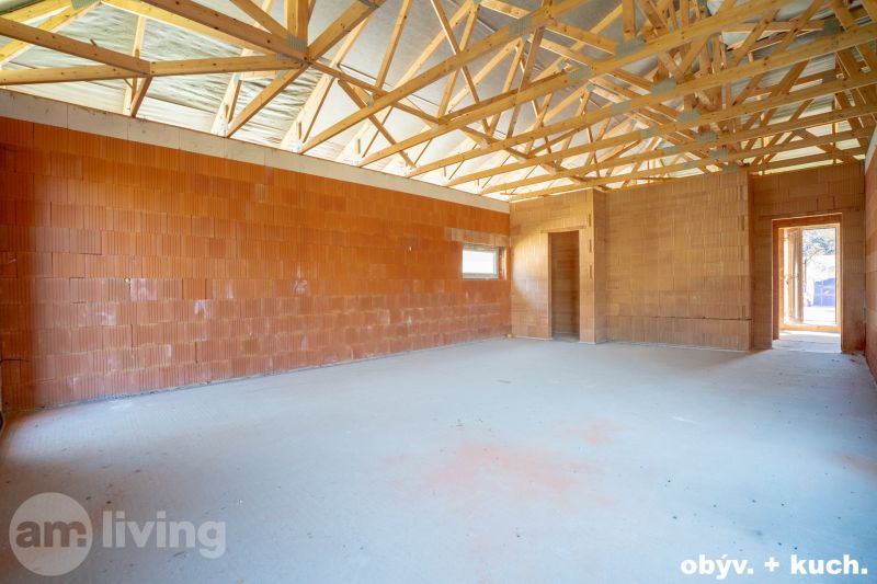 The interior of a family house with exposed roof beams and brick walls.