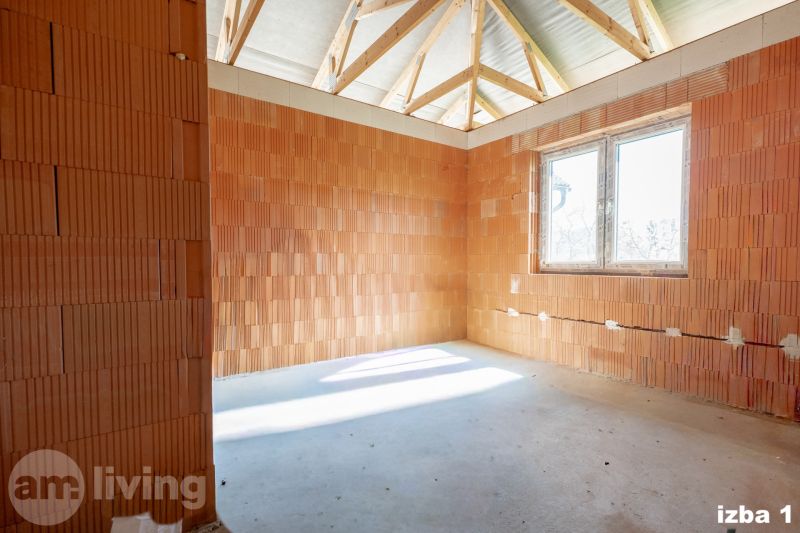 The interior of a room in a family house with wooden ceiling beams and a window.