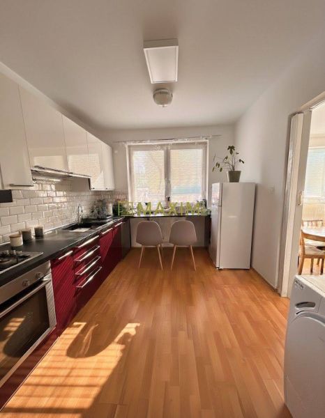 A kitchen with light cabinets, a floor with a wood decor in a 2-room apartment.