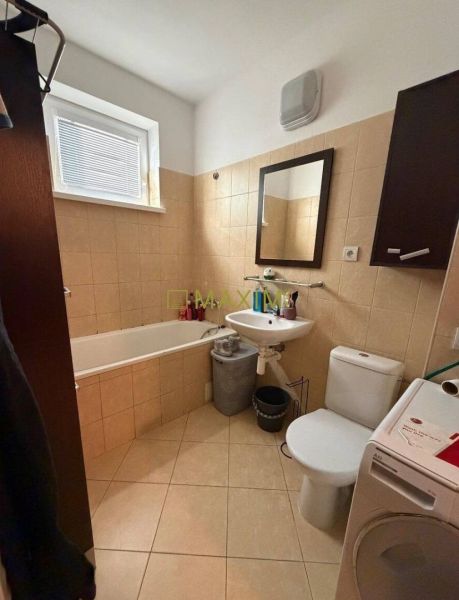 A bathroom in a 2-room apartment with a shower, sink, and washing machine.