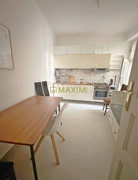 A kitchen in a 3-room apartment with a dining table and white furniture.