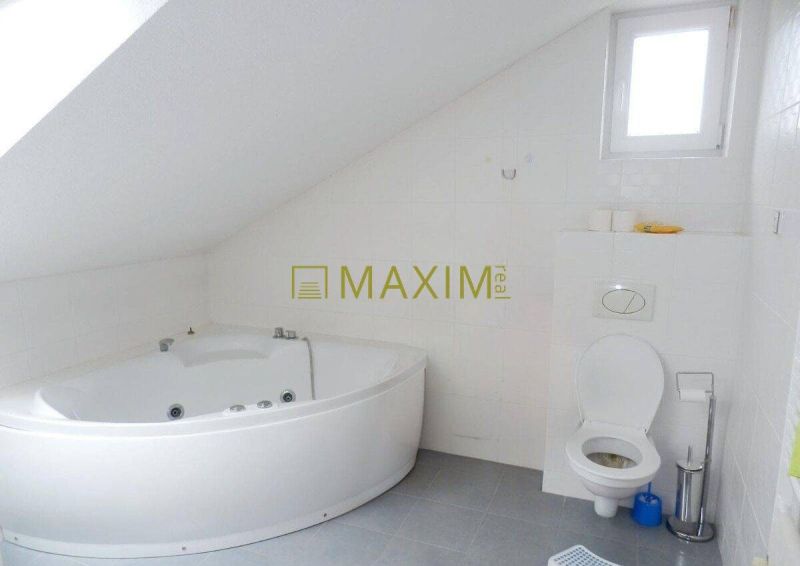 Bathroom with a bathtub and toilet in a cottage with an attic, white tiles.