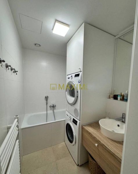 Bathroom with a bathtub, sink, and washing machine in a 3-room apartment; light tiles.