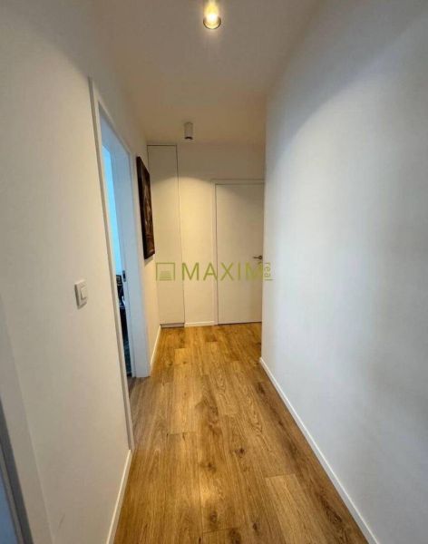 A hallway in a 3-room apartment with a wooden decor floor and white walls.