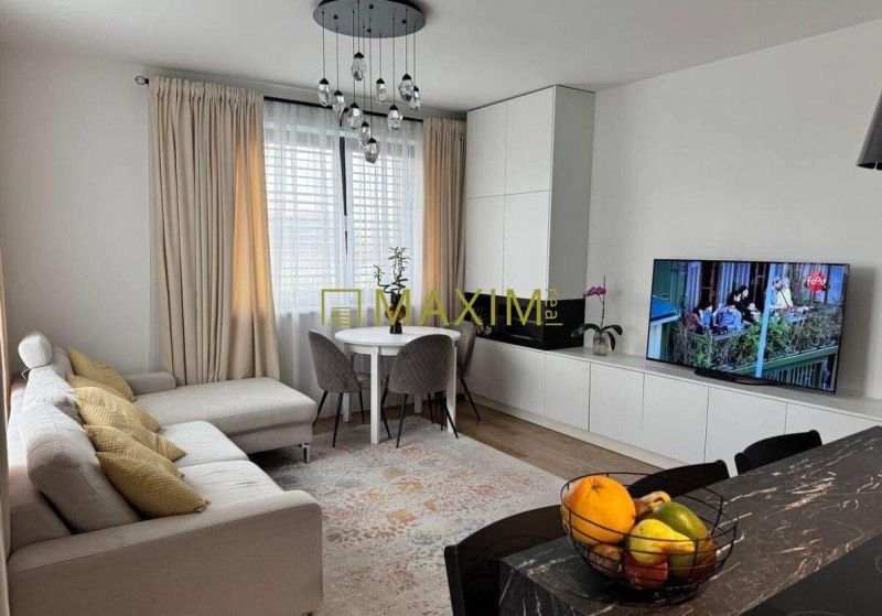 Living room in a 3-room apartment with a comfortable sofa, television, and dining area.