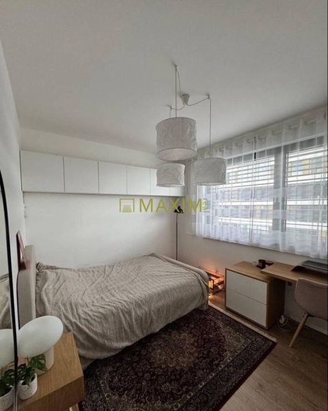 Bedroom in a 3-room apartment with wood-patterned flooring, carpet, desk, bed.