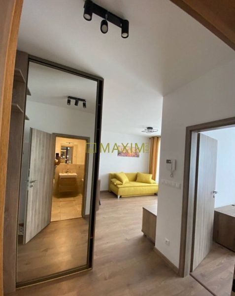 Interior of a 2-room apartment with a wooden decor floor, yellow sofa, and built-in wardrobe.