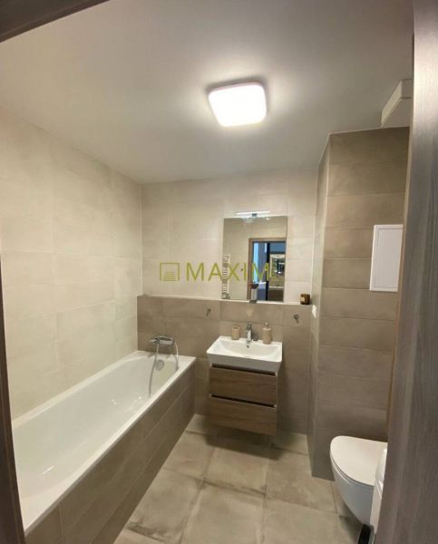 Bathroom in a 2-room apartment with a bathtub, sink, and light tiles.